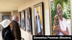 Visitors examine Artist Betsy Ashton's exhibition, "Portraits of Immigrants"