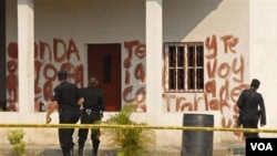 Agentes de la policía observan el mensaje pintado en la hacienda en el Caserío La Bomba, en La Libertad, al norte de Guatemala.