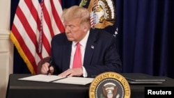 U.S. President Donald Trump signs executive measures for economic relief during a news conference amid the spread of the coronavirus disease, at his golf resort in Bedminster, N.J., Aug. 8, 2020. 