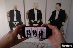 2025年2月8日，克里米亞一家美術館的參觀者在一個名為“雅爾塔2.0”的展覽上用手機拍攝一幅美國總統特朗普、俄羅斯總統普京和中國領導人習近平的三人畫像。