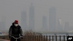 A man wearing a mask rides a bicycle along the Han river in Seoul, South Korea, Wednesday, March 6, 2019. (AP Photo/Lee Jin-man)