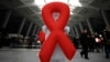 Imagem de arquivo: Voluntário exibe o símbolo da luta contra o SIDA numa estação de comboio em Pequim, China. 