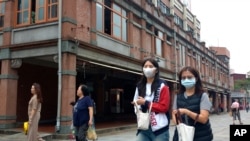 FILE - People wearing face masks to help curb the spread of the coronavirus walk on a street in Taipei, Taiwan, Oct. 19, 2020. 