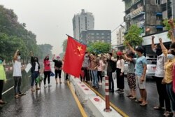 Anti-coup protesters hold a Chinese flag before burning it down during a demonstration against China in Yangon, Myanmar, April 5, 2021.