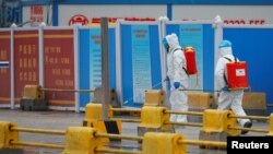 世衛組織專家組在中國調查新冠病毒溯源期間工人在武漢白沙洲商場噴灑消毒液。（2021年1月31日）