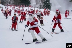 FILE - Skiers dressed in Santa Claus outfits hit the slopes for charity at the Sunday River Ski Resort, Sunday, Dec. 11, 2022, in Newry, Maine. (AP Photo/Robert F. Bukaty)