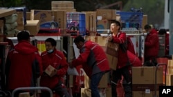 FILE - In this April 27, 2020, file photo, employees of a private delivery company sort out parcels at a distribution center in Beijing. Shortages of power, computer chips are affecting factories in Asia. (AP Photo/Andy Wong, File)