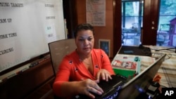 Aimee Rodriguez Webb works on her computer reading emails at her dinning room table that she set up as a virtual classroom for a Cobb County school, on Tuesday, July 28, 2020, in Marietta, Ga. (AP Photo/Brynn Anderson)