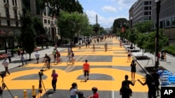 With the Washington Monument in the background people walk on the street leading to the White House after the words Black Lives Matter were painted on it by city workers and activists Friday, June 5, 2020, in Washington. (AP Photo/Manuel Balce Ceneta)