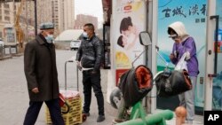 资料照片：2021年3月18日，戴着口罩的居民走在中国西部新疆地区阿克苏的街道上。(美联社照片)
