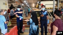 មន្ត្រី​សន្តិសុខ​ពិនិត្យ​មើល​សីតុណ្ហភាព​របស់​អ្នក​ចូល​ក្នុង​ផ្សារ​មួយ​កន្លែង នៅ​ក្នុង​ក្រុង Penang ប្រទេស​ម៉ាឡេស៊ី កាលពី​ថ្ងៃទី២៩ ខែឧសភា ឆ្នាំ២០២០។