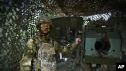 ARCHIVO: En esta imagen tomada el viernes 26 de abril de 2024 y publicada por el servicio de prensa del Ministerio de Defensa, un soldado ruso posa para una foto junto a un obús 2A65 "Msta-B" en una posición en un lugar no reveleado en Ucrania.