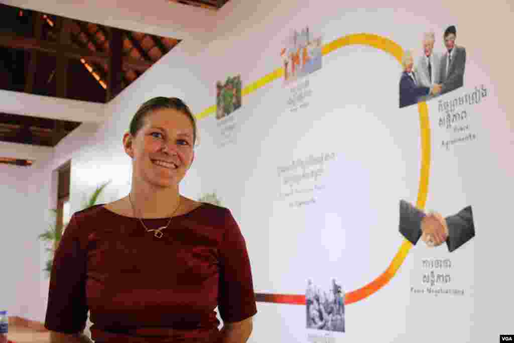 លោកស្រី​ Nikki Singer នាយក​សារមន្ទីរ​សន្តិភាព​កម្ពុជា​ឈរ​ពីមុខ​គំនូរ​លើ​ជញ្ជាំង​ដែល​បង្ហាញ​អំពី​ប្រវត្តិសាស្ត្រ​សង្ខេប​របស់​កម្ពុជា។ (រិទ្ធី​ ឧត្តម/VOA)