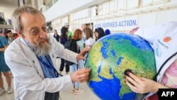 Environmental activists stage a protest with a earth globe during a demonstration at the venue of the COP28 United Nations climate summit in Dubai on Dec. 6, 2023.