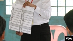 មន្ត្រីរៀបចំការបោះឆ្នោតលើកបង្ហាញសន្លឹកឆ្នោតមួយសន្លឹក​​ បន្ទាប់ពីការិយាល័យ​បោះឆ្នោតនៅទូទាំងប្រទេសបានបិទ នៅឃុំសារិកាកែវ ស្រុកល្វាឯម ខេត្តកណ្តាល ថ្ងៃអាទិត្យ​ ទី២៩ ខែកក្កដា​ ឆ្នាំ២០១៨។ (ស៊ុន ណារិន/VOA)