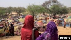 Des filles soudanaises qui ont fui le conflit dans la région soudanaise du Darfour et qui étaient auparavant déplacées à l'intérieur du Soudan, regardent des abris de fortune près de la frontière entre le Soudan et le Tchad, le 13 mai 2023.