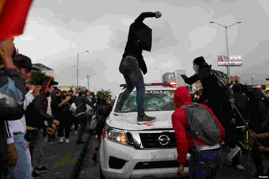 Manifestantes han destruido carros de policía, como en esta imagen donde un hombre se prepara para tirar una piedra a un vehículo policial.