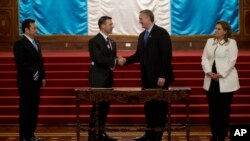 El ministro de Gobernación de Guatemala, Enrique Degenhart, segundo a la derecha, saluda al secretario de Seguridad Nacional de EE.UU., Kevin McAleenan durante una reunión bajo la vista del presidente de Guatemala, Jimmy Morales, izquierda.