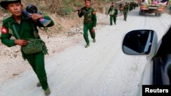FILE - Myanmar army soldiers walk along a road near Laukkai, Feb. 17, 2015.