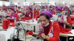 FILE: Garment workers sew clothes in a factory as they wait for visit by Prime Minister Hun Sen outside of Phnom Penh, Cambodia, Wednesday, Aug. 30, 2017. (AP Photo/Heng Sinith)