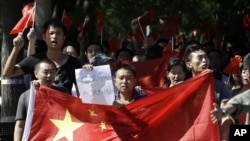 资料照片：2012年9月14日星期五，中国北京的反日抗议进入第四天，中国抗议者举着中国国旗和写着“日本狗，战败国”的纸游行到日本大使馆。