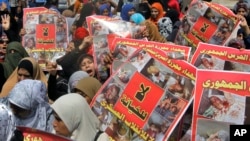 Wafuasi wa rais wa Misri aliyepinduliwa Mohamed Morsi wakibeba mabango yanayoonesha waathiriwa wa uvamizi wa kijeshi dhidi ya makambi yao Cairo. August 23, 2013.