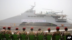 FILE - Members of Iran's Revolutionary Guard sit in front of a newly inaugurated high-speed warship, in the northern Persian Gulf port city of Bushehr, Iran, Sept. 13, 2016.
