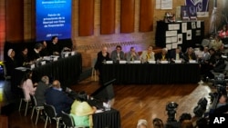 ARCHIVO - Excomandantes de las Fuerzas Armadas Revolucionarias de Colombia (FARC), arriba a la derecha, asisten a una audiencia ante la Jurisdicción Especial para la Paz sobre secuestros durante el conflicto interno de Colombia en Bogotá, Colombia, el 22 de junio de 2022.