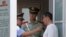 A Chinese police officer points as he speaks to a Chinese man held at a security checkpoint on Tiananmen Square in Beijing Wednesday, June 4, 2014.