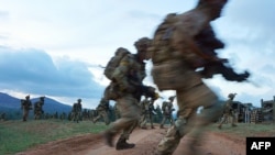 Des soldats traversent une route lors d'un exercice militaire simulé de l'unité d'entraînement de l'armée britannique au Kenya (BATUK) avec les Forces de défense du Kenya (KDF) au ranch ol-Daiga, haut sur le plateau de Laikipia au Kenya, le 26 mars 2018.