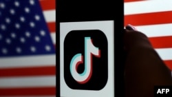 In this photo illustration, the social media application logo, TikTok is displayed on the screen of an iPhone on an American flag background on August 3, 2020 in Arlington, Virginia. - President Donald Trump said Monday that Chinese-owned hugely popular v