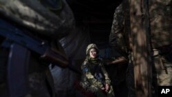 Un soldado ucraniano conversa con sus compañeros en una trinchera en la línea de separación entre terreno controlado por el gobierno ucraniano y territorio rebelde, el miércoles 23 de febrero de 2022, en Svitlodarsk, en el este de Ucrania. (AP Foto/Evgeniy Maloletka)