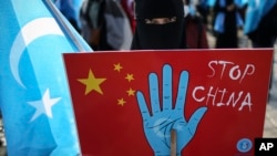 资料照：在土耳其首都伊斯坦布尔的维吾尔人手举抗议中国的标语牌参加示威集会。（2021年3月25日）