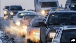 FILE - Car exhaust billows around commuter traffic in winter weather in Omaha, Nebraska, Feb. 1, 2013.