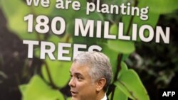 ប្រធានាធិបតី​កូឡុំប៊ី​លោក Ivan Duque ឈរ​នៅ​ក្បែរ​ផ្ទាំងរូប​ដែល​សំណេរ​ថា «យើង​កំពុង​ដាំ​ដើមឈើ​១៨០​លាន​ដើម» ក្នុង​អំឡុង​ពេល​សន្និសីទ​អង្គការ​សហ​ប្រជាជាតិ​លើក​ទី ២៦ ស្ដីពី​ការ​ប្រែប្រួល​អាកាសធាតុ (COP26) ក្នុង​ប្រទេស​ស្កុតលែន កាលពី​ថ្ងៃទី២ ខែវិច្ឆិកា ឆ្នាំ២០២១។ 