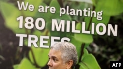 Colombia's President Ivan Duque reacts beneath a sign reading "We are planting 180 million trees" during the COP26 UN Climate Change Conference in Glasgow, Scotland on Nov. 2, 2021.