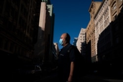 A man wearing a face mask walks across the street in Los Angeles, Aug. 7, 2020.