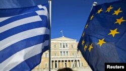A woman waves a Greek national flag and a European Union flag during a rally outside the parliament, calling on the government to clinch a deal with its international creditors and secure Greece's future in the Eurozone, in Athens, Greece, June 18, 2015.
