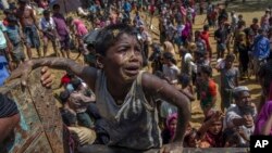 A Rohingya Muslim boy, who crossed over from Myanmar into Bangladesh, pleads with aid workers to give him a bag of rice near Balukhali refugee camp, Bangladesh, Thursday, Sept. 21, 2017. (AP Photo/Dar Yasin)