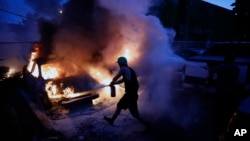 Građani pokušavaju da ugase požar koji je izbio tokom nereda u Mineapolisu, 29. maj 2020 (Foto: AP/John Minchillo)