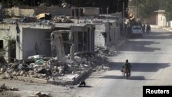 A rebel fighter rides past damaged buildings in al-Rai town, northern Aleppo countryside, Syria, Oct. 2, 2016. 