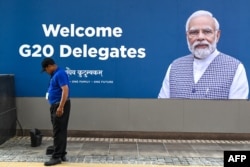 سات ستمبر کو ایک کارکن جی ٹوئینٹی کمیونیکیشن بل بورڈ کے سامنے صفائی کر رہا ہے جہاں بھارتی ۔وزیر اعظم نریندرا مودی کی پورٹریٹ لگی ہوئی ہے۔ 7 ستمبر 2023