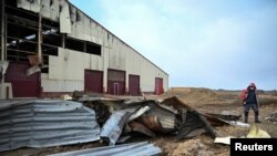 Вработен оди надвор од штала, која беше оштетена од напад на руско беспилотно летало, среде рускиот напад врз Украина, во фарма во регионот Чернихив, Украина, 13 декември 2024 година