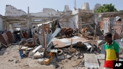 A man walks near destroyed buildings after a bomb blast in the capital city of Mogadishu, Somalia, Dec. 22, 2018. Police say a suicide car bomb exploded near the presidential palace killing and wounding a number of people.