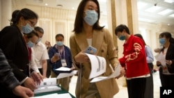 Journalists line up for copies of a news release outlining the results of China's latest population census before a press conference at the State Council Information Office in Beijing, May 11, 2021. 