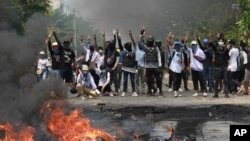 Anti-coup protesters gesture with a three-fingers salute, a symbol of resistance during a demonstration during by police crack down in Thaketa township Yangon, Myanmar, Saturday, March 27, 2021.