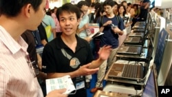 FILE - An exhibitor details the latest specifications of his laptop computers to a visitor during a computer trade show in Taipei, Taiwan.