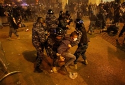 FILE - Riot police officers beat anti-government protesters during a protest near the parliament square, in downtown Beirut, Lebanon, Dec. 15, 2019.