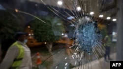 Saudi airport personnel are pictured behind shrapnel-riddled glass at Abha airport in the popular mountain resort of Abha in the southwest of Saudi Arabia on August 31, 2021.