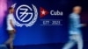 Hombres caminan cerca de un cartel de la Cumbre del G77 + China durante la inauguración de la sala de prensa en La Habana, el 13 de septiembre de 2023